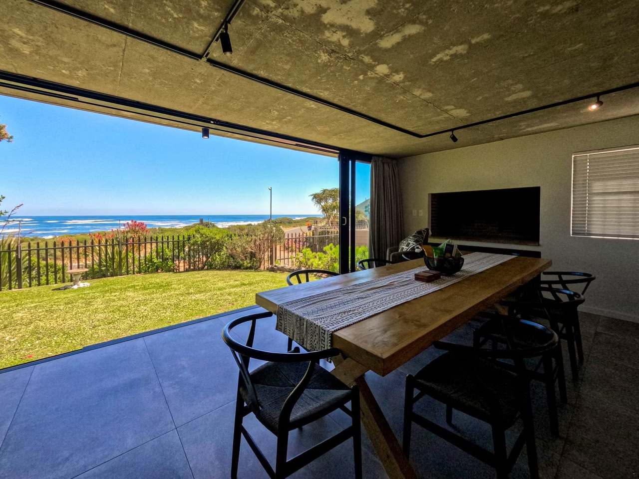 Dining room at Imoyo Ocean Villa opening onto the lawn and Walker Bay ocean view in Sandbaai