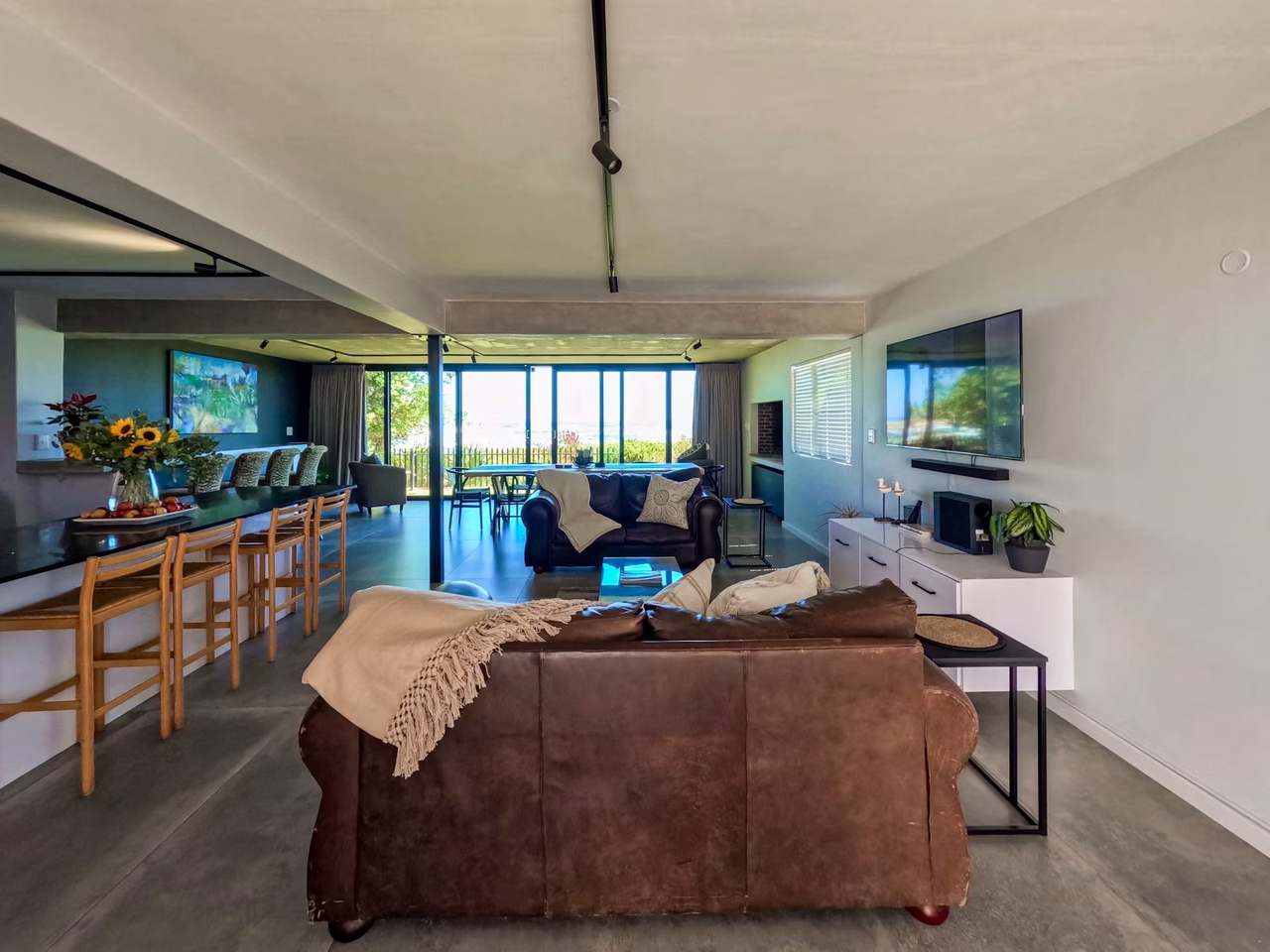Open-plan lounge and kitchen at Imoyo Ocean Villa with leather sofas, island seating and indoor-outdoor living