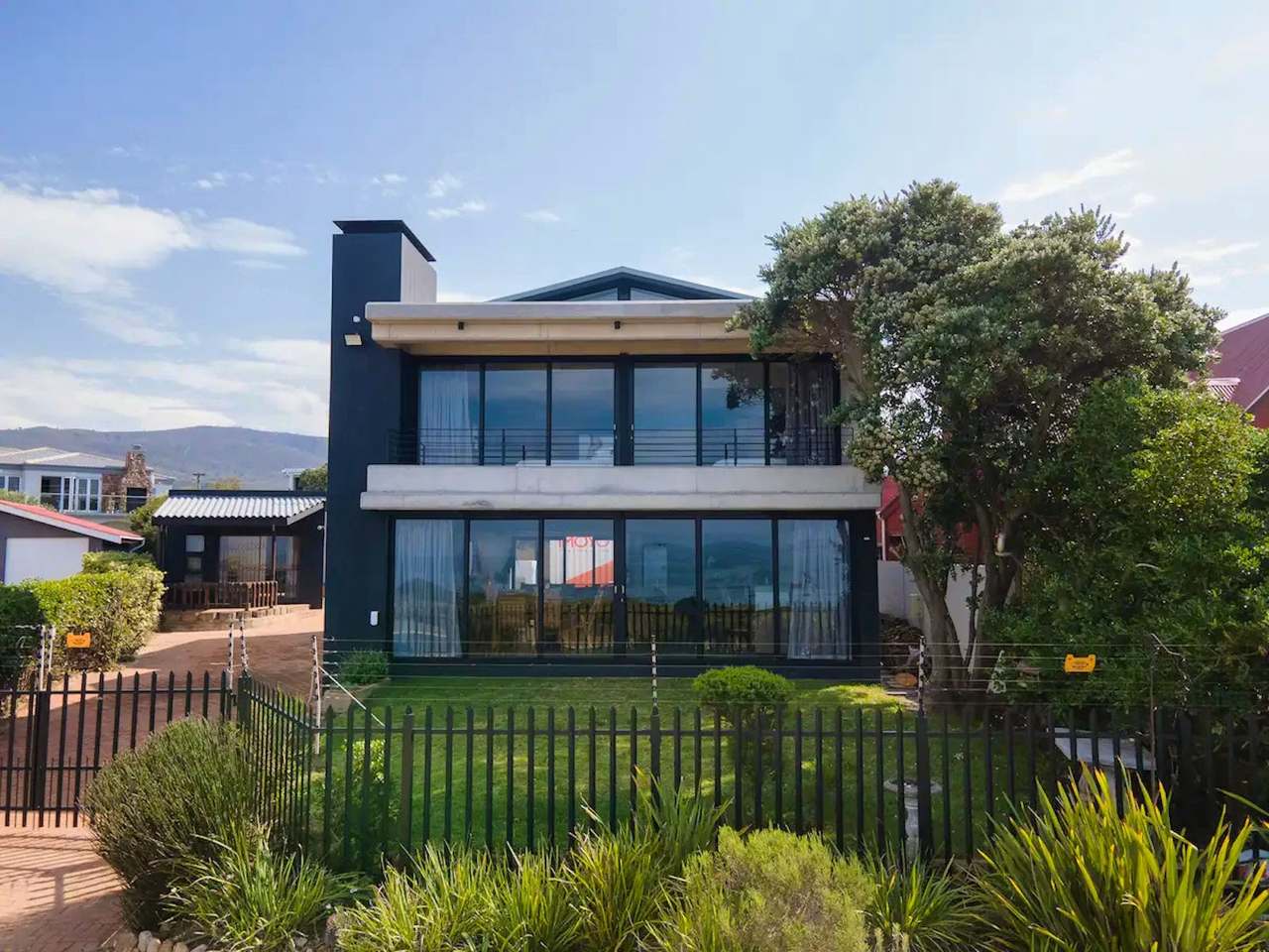 Contemporary Imoyo Ocean Villa holiday rental in Sandbaai, Hermanus with two-storey glass facade and garden